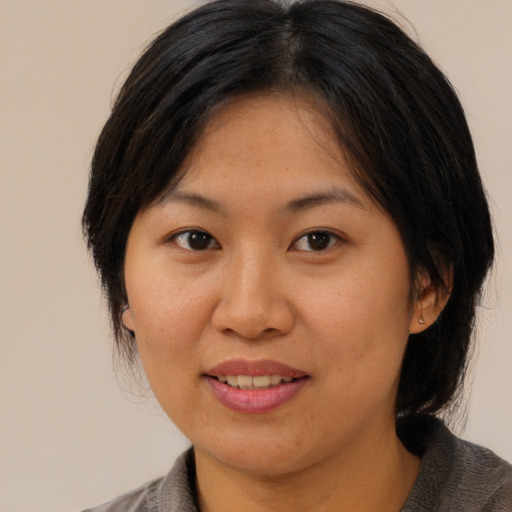 Joyful asian adult female with medium  brown hair and brown eyes