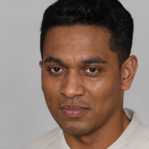 Joyful black young-adult male with short  black hair and brown eyes