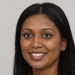 Joyful black young-adult female with long  brown hair and brown eyes