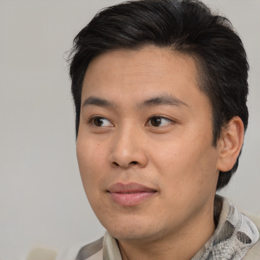 Joyful asian young-adult male with short  brown hair and brown eyes