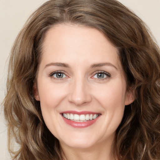 Joyful white young-adult female with long  brown hair and green eyes