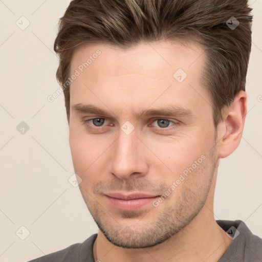 Joyful white young-adult male with short  brown hair and grey eyes