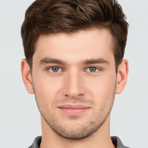 Joyful white young-adult male with short  brown hair and grey eyes