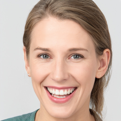 Joyful white young-adult female with medium  brown hair and grey eyes