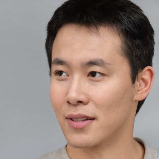 Joyful asian young-adult male with short  black hair and brown eyes