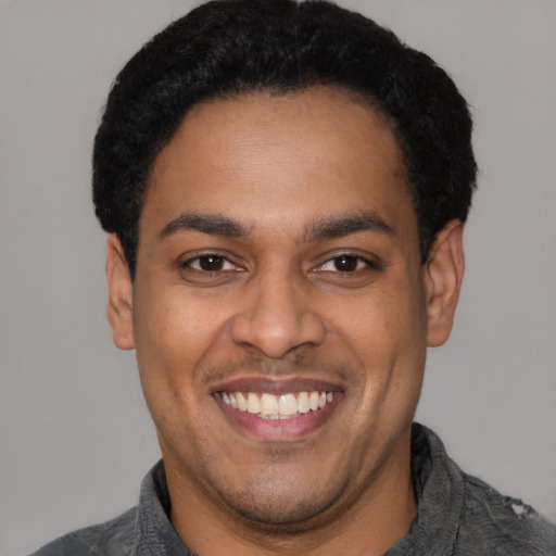 Joyful latino young-adult male with short  black hair and brown eyes