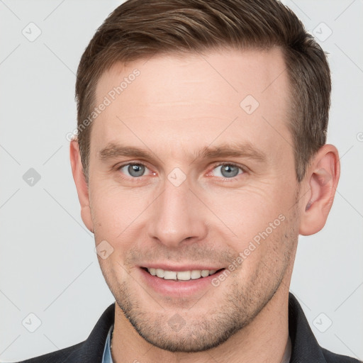 Joyful white young-adult male with short  brown hair and grey eyes