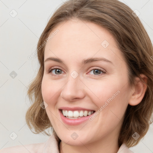 Joyful white young-adult female with medium  brown hair and blue eyes