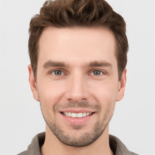 Joyful white young-adult male with short  brown hair and grey eyes