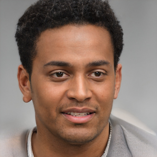 Joyful black young-adult male with short  brown hair and brown eyes