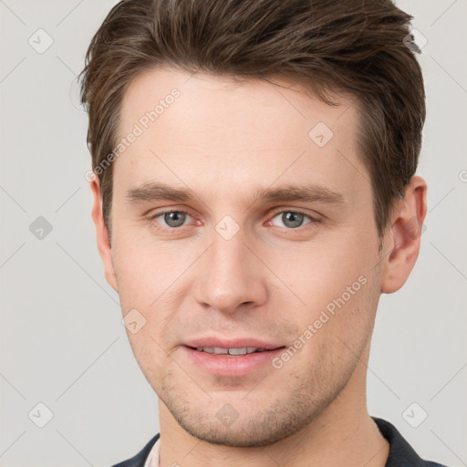 Joyful white young-adult male with short  brown hair and grey eyes