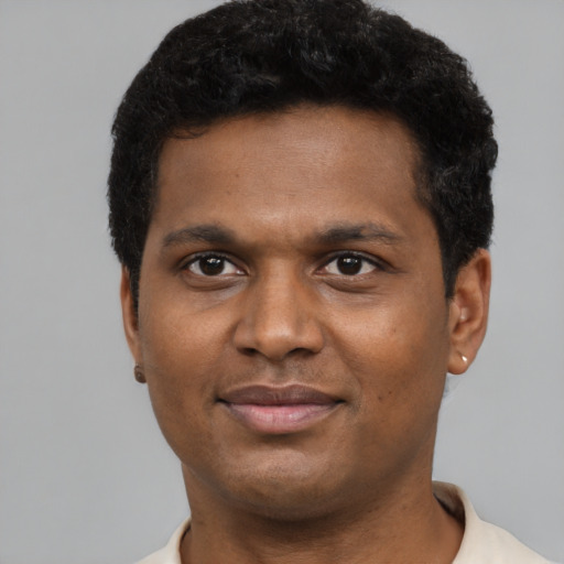 Joyful black young-adult male with short  brown hair and brown eyes