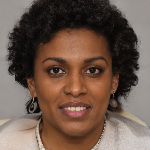 Joyful black young-adult female with long  brown hair and brown eyes