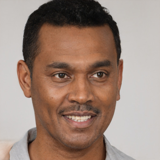 Joyful black young-adult male with short  black hair and brown eyes