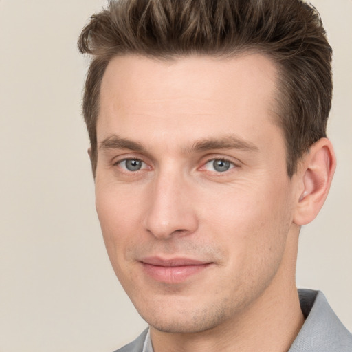 Joyful white young-adult male with short  brown hair and grey eyes