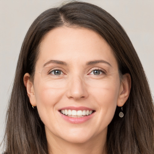 Joyful white adult female with long  brown hair and grey eyes