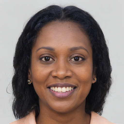 Joyful black young-adult female with long  brown hair and brown eyes