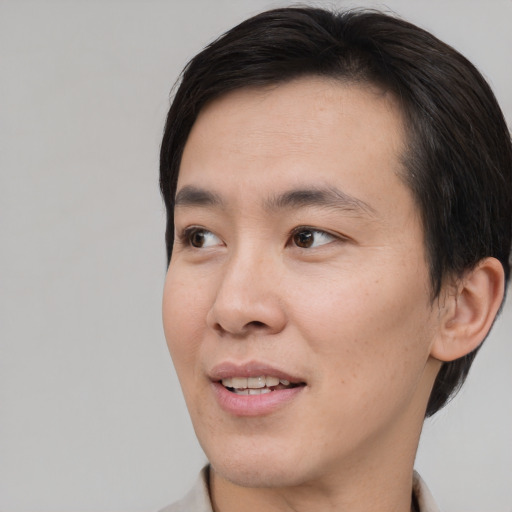 Joyful asian young-adult male with short  brown hair and brown eyes