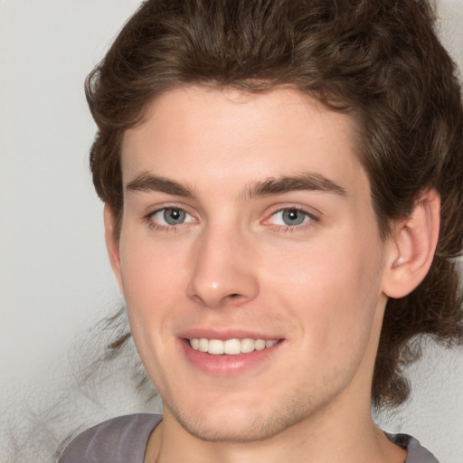 Joyful white young-adult male with medium  brown hair and grey eyes