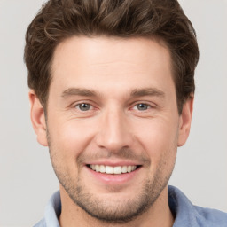 Joyful white young-adult male with short  brown hair and grey eyes