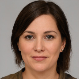 Joyful white young-adult female with medium  brown hair and grey eyes