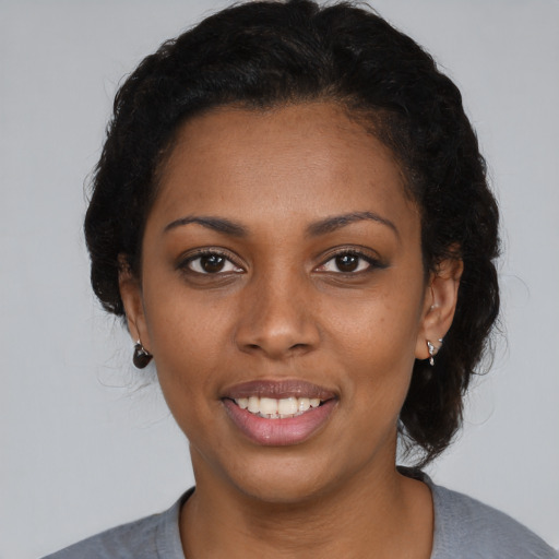 Joyful black young-adult female with short  black hair and brown eyes