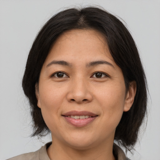 Joyful asian adult female with medium  brown hair and brown eyes