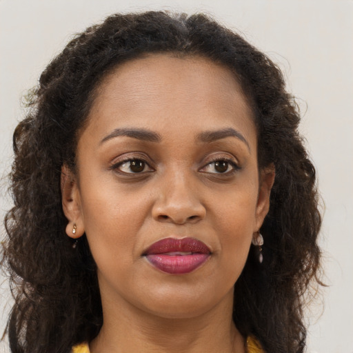 Joyful black young-adult female with long  brown hair and brown eyes