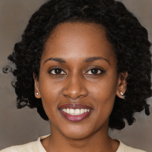 Joyful black young-adult female with short  black hair and brown eyes