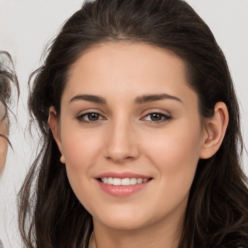 Joyful white young-adult female with long  brown hair and brown eyes