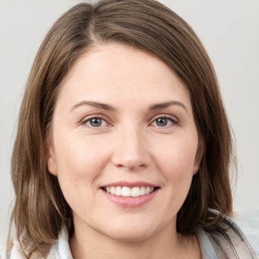 Joyful white young-adult female with medium  brown hair and grey eyes