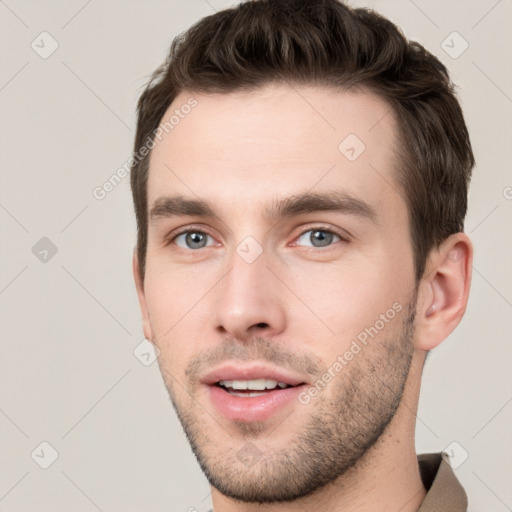 Joyful white young-adult male with short  brown hair and grey eyes