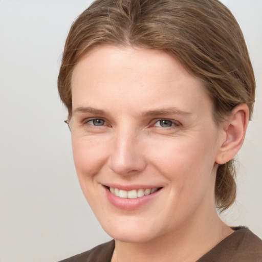 Joyful white young-adult female with medium  brown hair and grey eyes