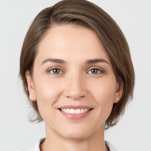 Joyful white young-adult female with medium  brown hair and grey eyes