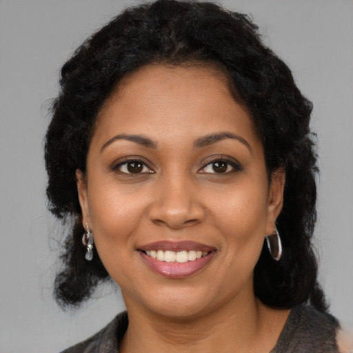 Joyful black young-adult female with long  brown hair and brown eyes