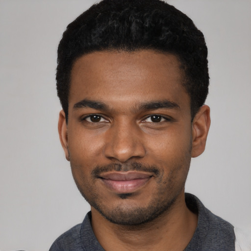 Joyful black young-adult male with short  black hair and brown eyes
