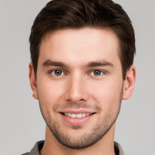 Joyful white young-adult male with short  brown hair and grey eyes