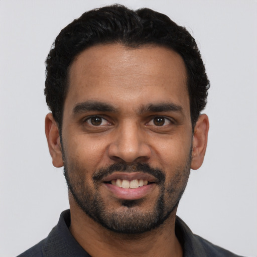 Joyful latino young-adult male with short  black hair and brown eyes