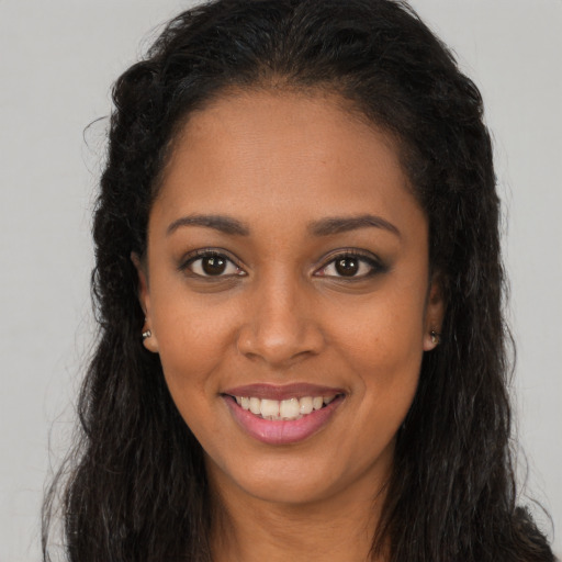 Joyful black young-adult female with long  brown hair and brown eyes