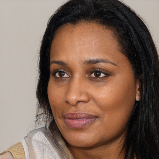 Joyful black young-adult female with long  brown hair and brown eyes