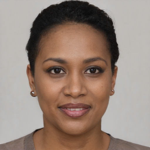 Joyful black young-adult female with short  black hair and brown eyes