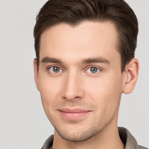 Joyful white young-adult male with short  brown hair and grey eyes