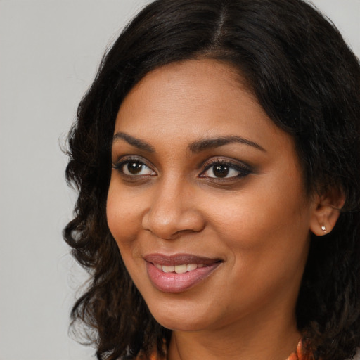 Joyful black young-adult female with long  brown hair and brown eyes