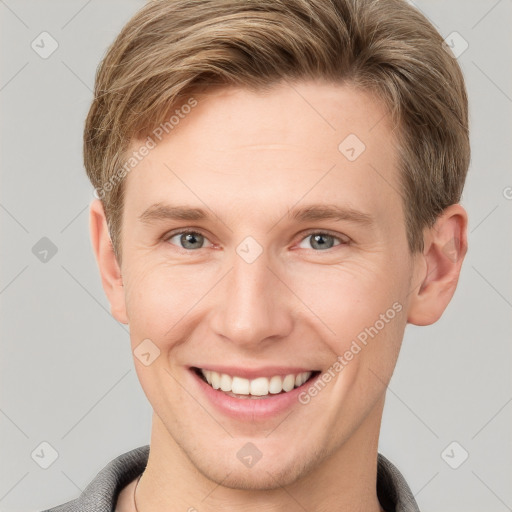 Joyful white young-adult male with short  brown hair and grey eyes