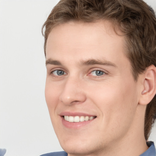 Joyful white young-adult male with short  brown hair and blue eyes