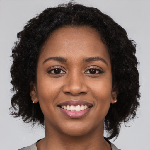 Joyful black young-adult female with long  black hair and brown eyes