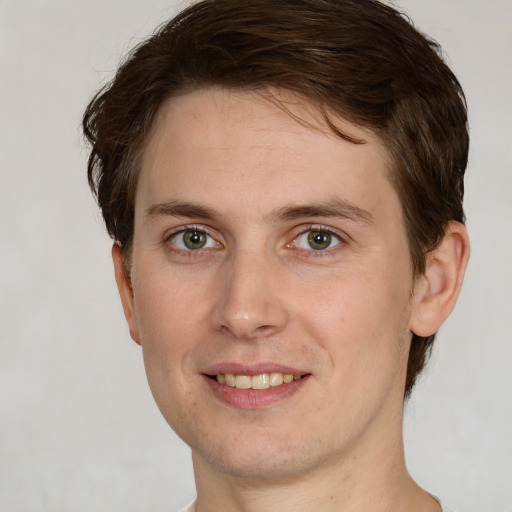 Joyful white young-adult male with short  brown hair and green eyes