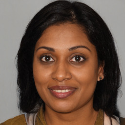 Joyful black young-adult female with long  brown hair and brown eyes