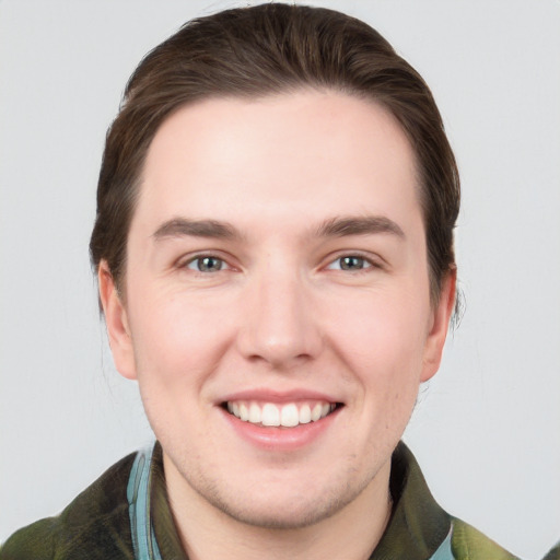 Joyful white young-adult male with short  brown hair and grey eyes