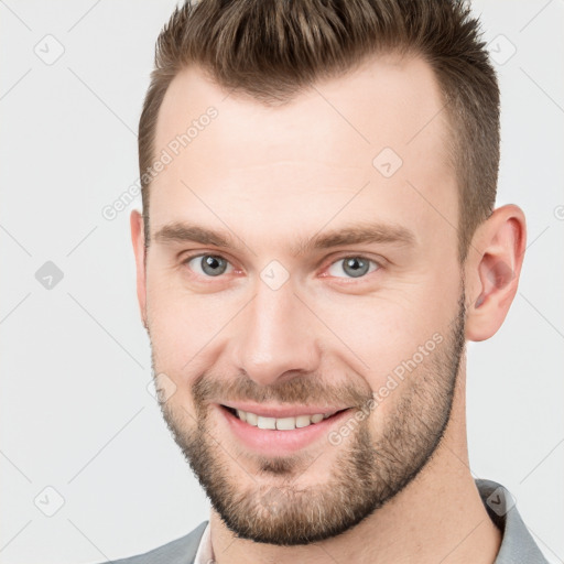 Joyful white young-adult male with short  brown hair and grey eyes